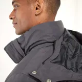 Campera acolchada de corte recto en color gris, con capucha ajustable, cierre frontal de cremallera y botones a presión, y bolsillos laterales.