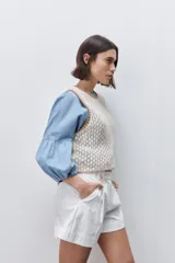 Short de tiro alto confeccionado en algodón, con calce relajado y silueta recta. Presenta pinzas delanteras, bolsillos laterales y botones decorativos en la cintura.