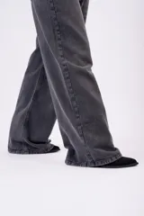 Jean wide-leg de tiro bajo, color gris carbón deslavado, con diseño amplio y fluido, bolsillos laterales y traseros clásicos.
