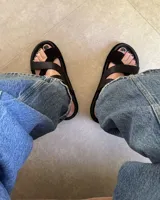 Sandalias negras de cuero vacuno con tiras cruzadas y hebilla lateral.