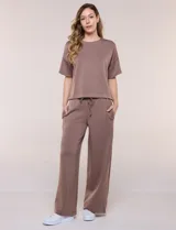 Conjunto de buzo de manga corta con hombros caídos y escote redondo, acompañado de un pantalón tipo wide leg de tiro alto con cintura elástica y cordón de ajuste, en color verde.