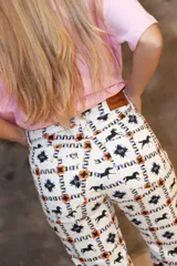 Pantalón de jean de corte recto con estampado integral de caballos, estrellas y motivos geométricos. Presenta aberturas en el ruedo y cierre frontal con botón.