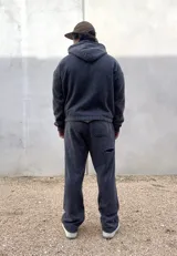Pantalón de jogging color negro con efecto acid wash, corte holgado y bolsillos laterales. Presenta un pequeño parche bordado con la inscripción de la marca en la pierna izquierda.