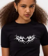 Remera de algodón con elastano, de corte ajustado, manga corta y cuello redondo. Presenta una estampa frontal de corazón con diseño tribal en color blanco sobre fondo negro.