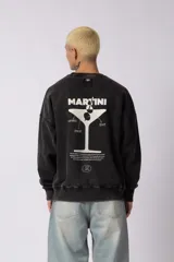 Buzo de cuello redondo con calce oversize y efecto lavado (washed). Presenta una estampa gráfica en la espalda con el diseño de una copa de martini y texto descriptivo.