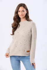 Buzo tejido de punto en color beige, con cuello redondo, mangas largas y puños acanalados. Presenta un delicado diseño bordado con motivos florales dispersos en el frente y una etiqueta de cuero sintético en el ruedo.