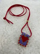 Collar con dije rectangular bordado con un corazón rojo y detalles de mostacillas de colores.