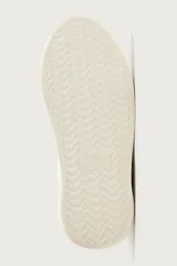 Zapatilla deportiva de diseño monocolor en tono crema, con cordones al tono y suela de plataforma con volumen.