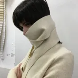 Buzo color crudo de lana merino afieltrada, con cuello alto que se ata con un lazo al frente.