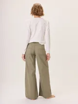 Remera blanca de manga larga con escote en V y detalles de alforzas verticales en el frente y mangas.