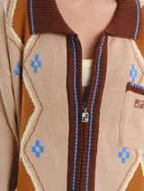 Campera tejida en jacquard con cierre frontal, cuello tipo polo y bolsillos delanteros. Diseño multicolor con estampado geométrico de rombos y detalles bordados a mano.