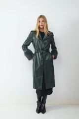 Trench largo de efecto cuero en color verde oscuro, con acabado brillante, cuello solapa, cinturón ajustable a la cintura y puños con detalle de pelo sintético.