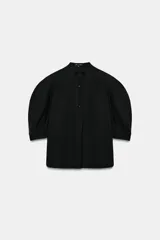 Camisa de cuello redondo y manga corta abullonada, color negro, de corte recto con aberturas laterales y cierre frontal con botones. Perteneciente a la colección ZARA Woman Collection.