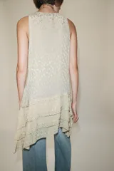 Vestido corto de viscosa color crudo, con escote redondo, manga sisa y diseño en jacquard con aplicaciones de abalorios. Presenta múltiples paneles superpuestos y bajo asimétrico.