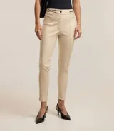 Pantalón legging color beige con frente de poliuretano que imita cuero y parte trasera de punto roma. Presenta detalle de cadena metálica en la cintura y cierre frontal.