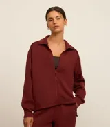 Campera deportiva negra confeccionada en microfibra pesada, con cuello alto doblado, cremallera delantera con cordón en el tirador y puños ajustados.