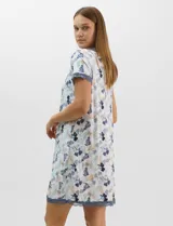 Camisón corto de tejido soft, color blanco con estampado floral y de hojas en tonos azules y marrones. Cuenta con mangas cortas y escote en V con terminaciones de encaje azul en el cuello, las mangas y el ruedo.