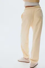 Jogging de felpa color amarillo pálido, con interior cepillado suave. Presenta cintura elástica fruncida con cordón ajustable y elástico revestido en los bajos.