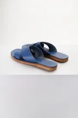 Sandalias bajas de cuero azul con tiras anchas cruzadas sobre el empeine y suela plana color madera.