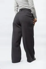 Pantalón de corte sastrero y tiro bajo, con diseño de pierna ancha y holgada. Presenta cierre frontal con botón y bolsillos laterales.