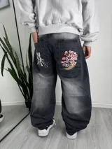 Pantalón de jean baggy color gris con efecto acid wash, corte holgado y bordados orientales en los bolsillos traseros.