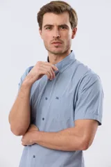 Camisa de manga corta de algodón en color celeste con microdiseño geométrico a cuadros, cuello camisero y bolsillo frontal con logo bordado.