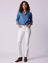 Camisa de manga larga en tela denim de color azul medio, con cuello clásico, botones frontales y dos bolsillos de parche con solapa en el pecho.