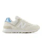 Championes urbanos New Balance modelo 574, color beige con detalles en blanco y talón metalizado en celeste. Confeccionados en una combinación de gamuza y malla, cuentan con el logo N característico en los laterales y entresuela ENCAP para mayor amortiguación y sujeción.