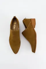Zapato tipo botineta de gamuza color marrón, con diseño de corte lateral, punta fina y taco bajo de madera. Cuenta con cierre en la parte trasera.