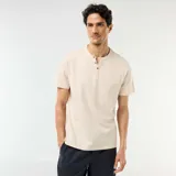 Remera de manga corta color beige, con cuello tunecino y cartera con botones frontales.
