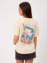 Remera blanca de corte holgado, con cuello redondo y mangas cortas. Presenta un pequeño estampado en el pecho con diseño floral y tipografía.