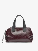 Bolso tipo bowling de Adolfo Dominguez, color borgoña oscuro con acabado brillante y textura craquelada. Posee asas de mano negras y un cordón ajustable lateral.