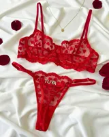 Conjunto de lencería de dos piezas rojo confeccionado en tul con diseño de corazones bordados. Incluye corpiño con aro y tirantes regulables, y bombacha colaless regulable con detalle de letras de strass.
