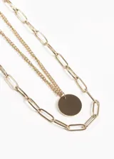Collar doble dorado con cadena de eslabones grandes y cadena fina con dije circular.
