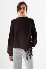 Sweater negro de tejido acanalado, con cuello redondo y un detalle asimétrico en el ruedo inferior con flecos largos.