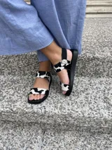 Sandalias bajas con suela negra y tiras de cuero con estampado de vaca.
