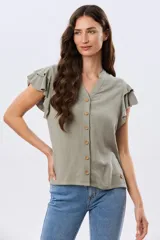 Camisa de lino y viscosa color beige, con cuello mao, escote en V y botones frontales de madera. Presenta mangas cortas con volados delicados.