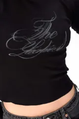 Remera de manga larga gris de corte ajustado, con cuello redondo y estampado frontal con la frase "The Luckiest".