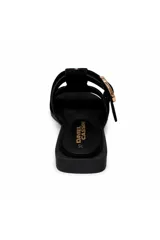 Zueco de gamuza negra con diseño trenzado tipo fisherman, hebilla metálica dorada y tachas decorativas.