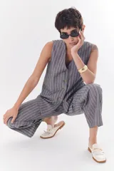 Pantalón de corte recto y relajado, confeccionado en una mezcla de lino y algodón con diseño de rayas verticales en tonos grises. Presenta un estilo sastrero ideal para diversas ocasiones.