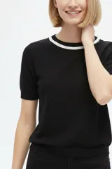 Remera de algodón al cuerpo en color negro, con mangas cortas y cuello redondo adornado con cordón blanco.