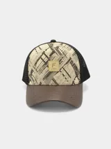 Gorra trucker con visera curva de cuero marrón, paneles frontales estampados con diseño abstracto en tonos beige y negro, y paneles traseros de malla negra.
