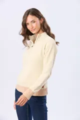 Buzo tejido combinado de color beige, con cuello alto, medio cierre metálico y puños y ruedo acanalados en tono tostado.