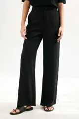 Pantalón de vestir color beige, de corte palazzo y tiro alto. Incluye cinturón de cadena plateada.