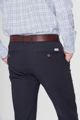Pantalón de gabardina azul marino de corte slim fit y tiro medio, con bolsillos traseros ojalados con botón y presillas para cinturón.