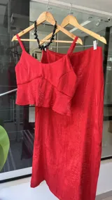 Falda midi de corte recto, confeccionada en tela satinada con textura arrugada en color bordó. Presenta un diseño elegante y fluido.