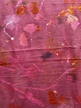 Mantel rectangular de lino color rosa con estampado de hojas y flores en tonos naranja, marrón y blanco.