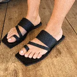 Sandalias chatas negras de cuero vacuno, con base cuadrada y tiras anchas sobre el empeine y el dedo gordo.