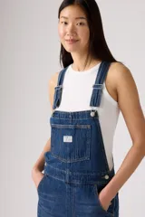 Overall de jean en color azul clásico con lavado desgastado. Presenta un diseño de corte recto y holgado, con bolsillo frontal en el pecho, tirantes ajustables con hebillas metálicas y bolsillos laterales.