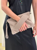 Sobre/cartera de cuero gamuza color beige, con diseño geométrico en la solapa. Incluye una correa larga para usar al hombro o como bandolera y una correa corta para la muñeca, ambas desmontables.